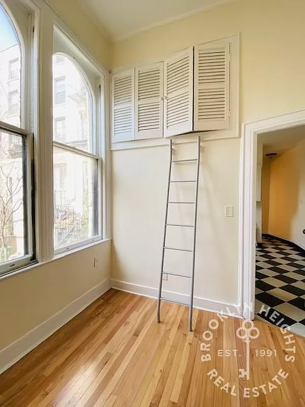 bedroom with a ladder to high storage with shutter doors
