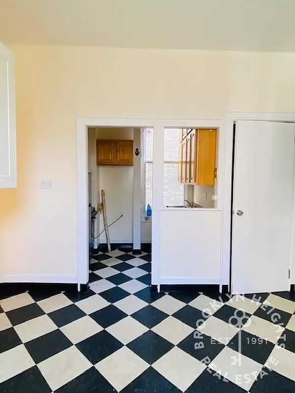 dining area with view into kitchen, both with black and white checkerboard floor tiles