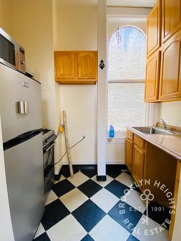 kitchen with wood cabinets and black and white checkerboard floor tiles