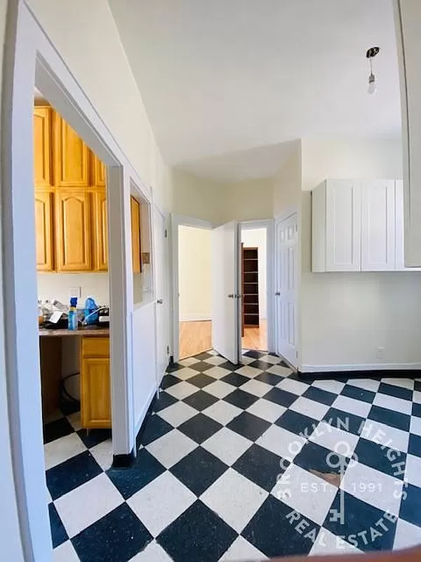 dining area with view into kitchen, both with black and white checkerboard floor tiles