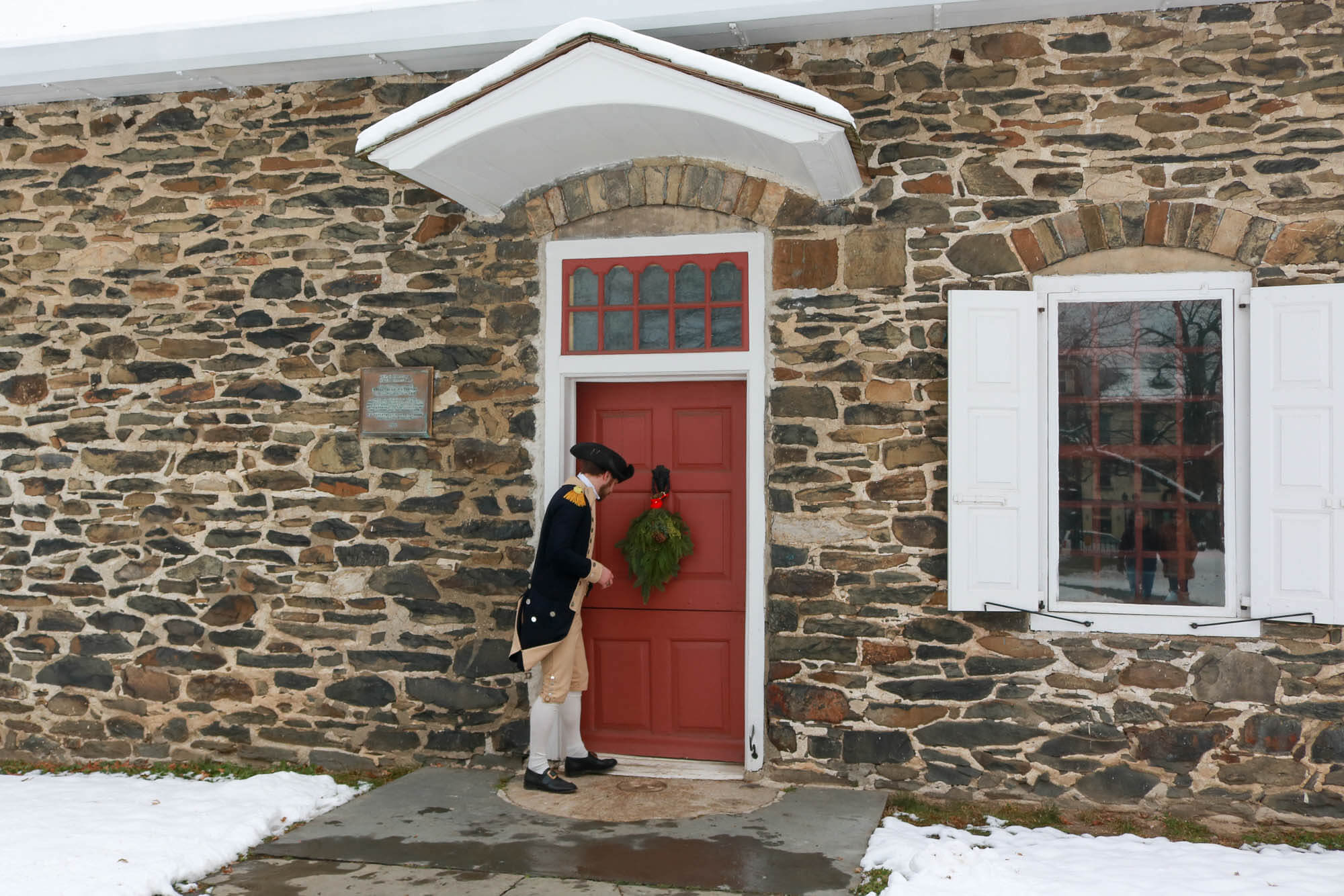 costumed soldier at the front door of the stone building