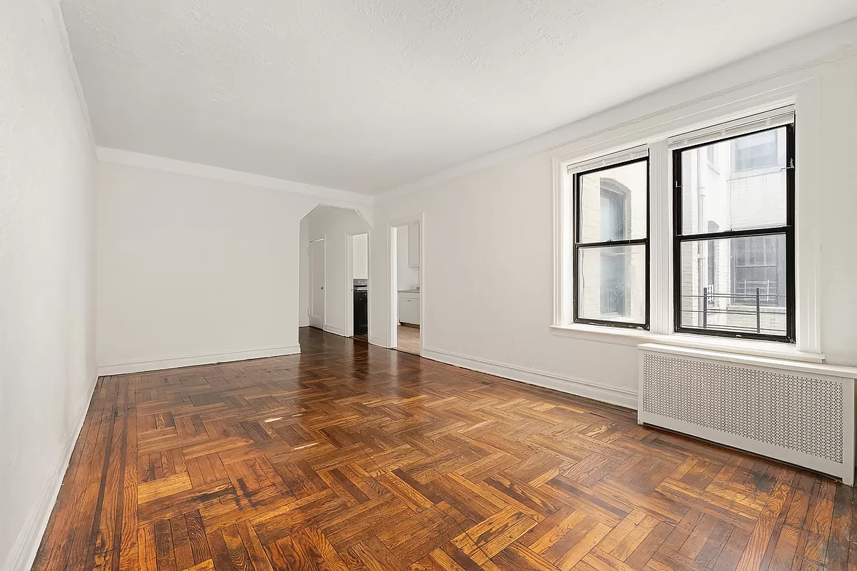 living room with wood floor, two windows and arched opening to foyer