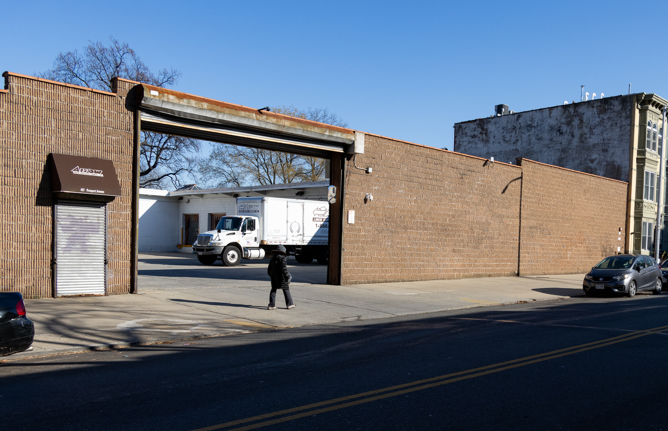 person walking by the parking lot with arrow linen truck visible