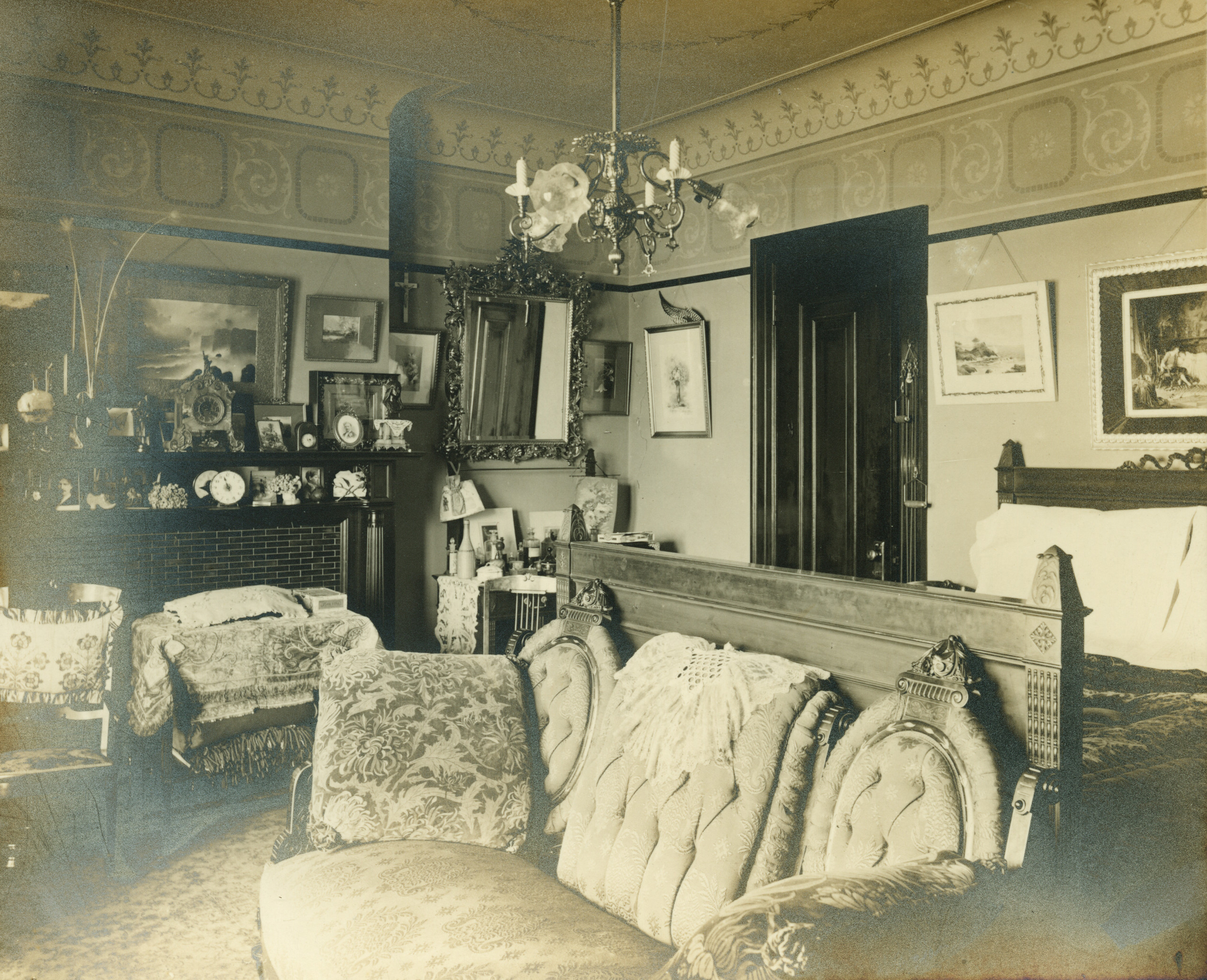 bedroom with love seat at foot of bed and a mantel