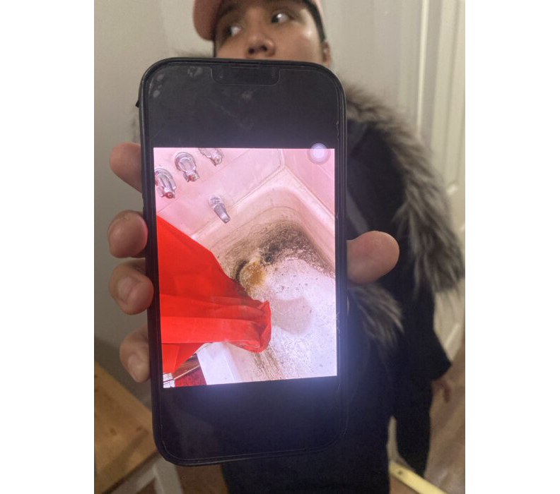 a tenant holds a phone with an image of her bathtub