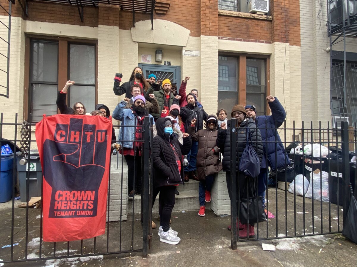 tenants stand outside the entrance to their crown heights building in protest