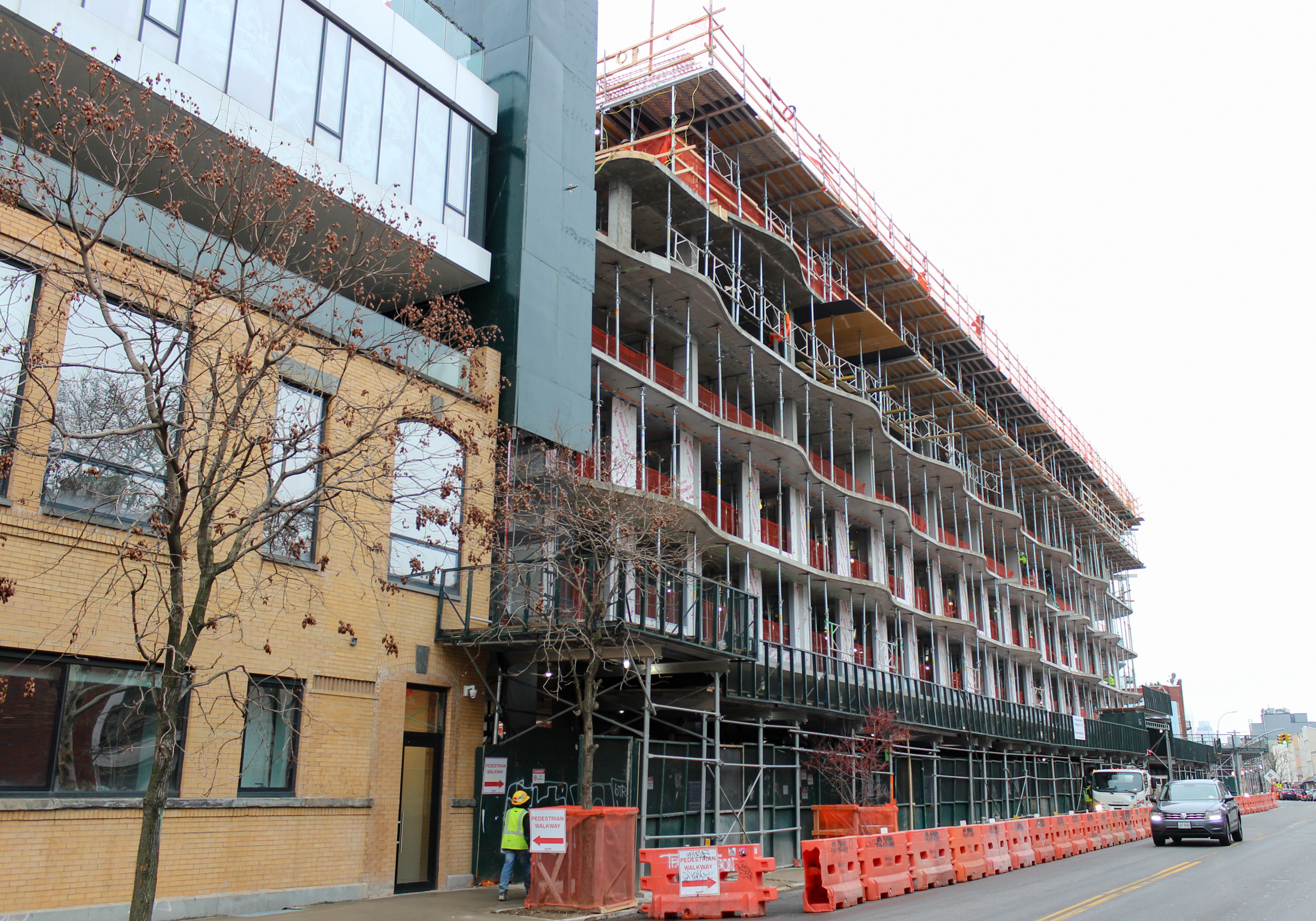 a yellow brick building and the new building under construction