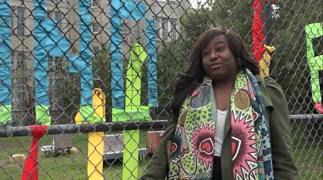 flatbush - woman standing in front of the chain link fence surrounding the burial ground