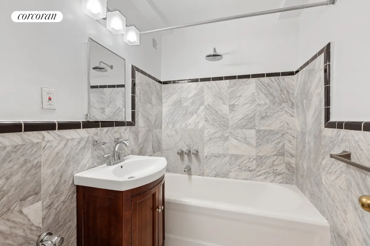 bathrom with wood vanity and marble wall tiles
