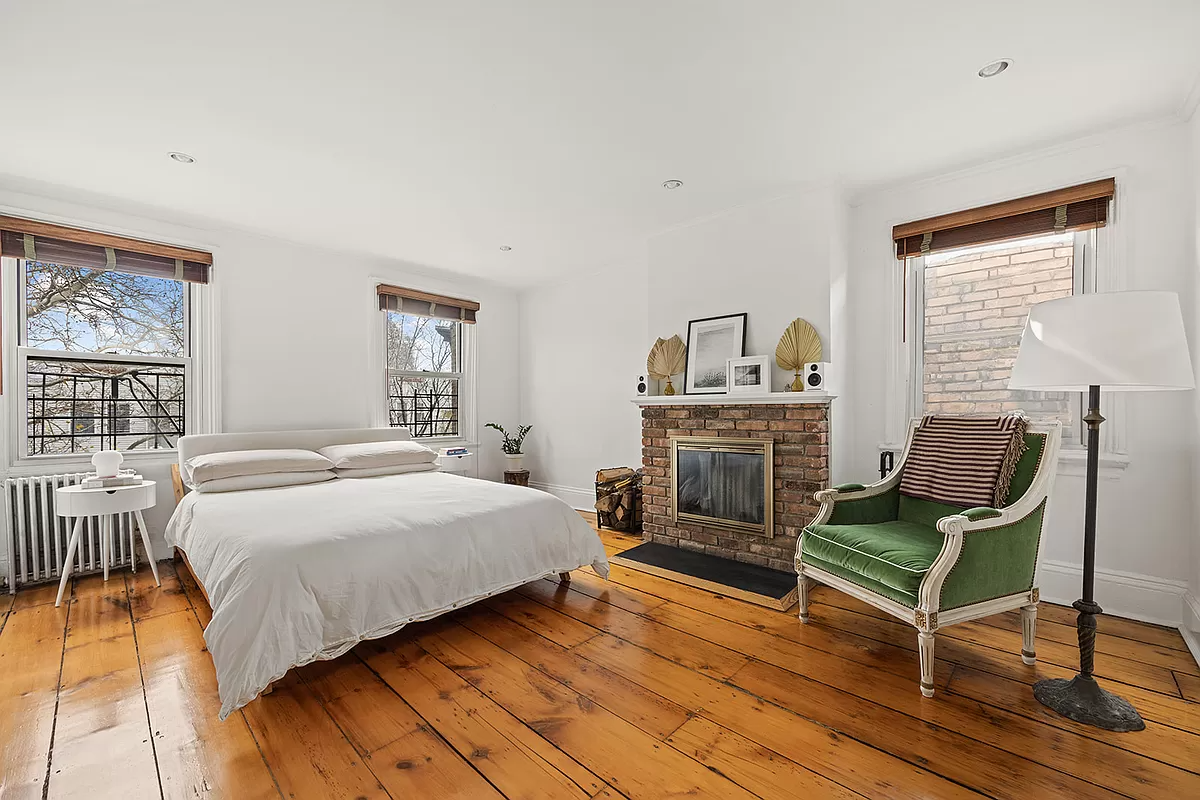 bedroom with brick fireplace and wide floorboard