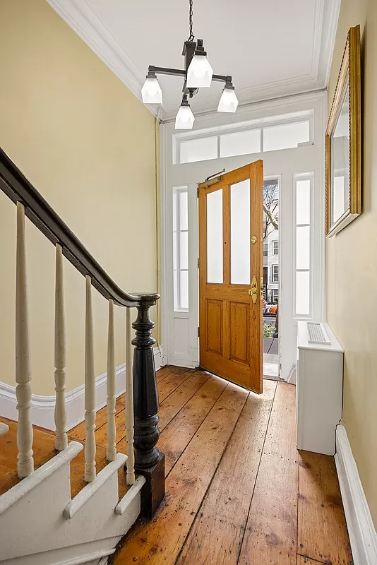 entry with wide floor boards and an original newel post