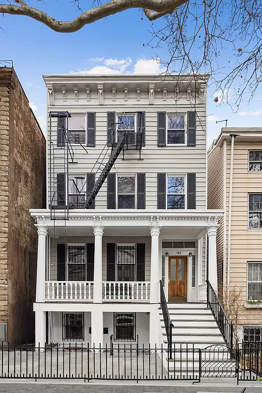 exterior with gray siding, bracketed cornice and white columned porch