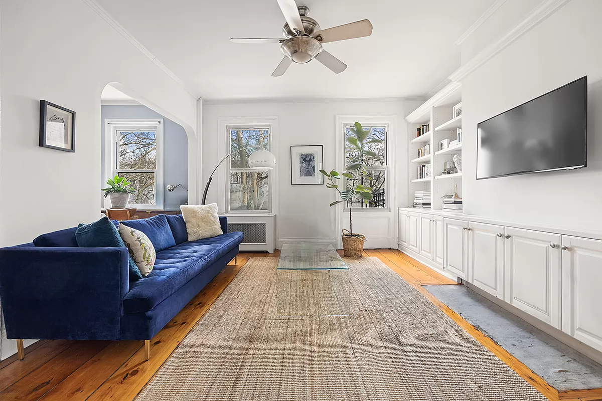 living room with built-ins and a ceiling fan