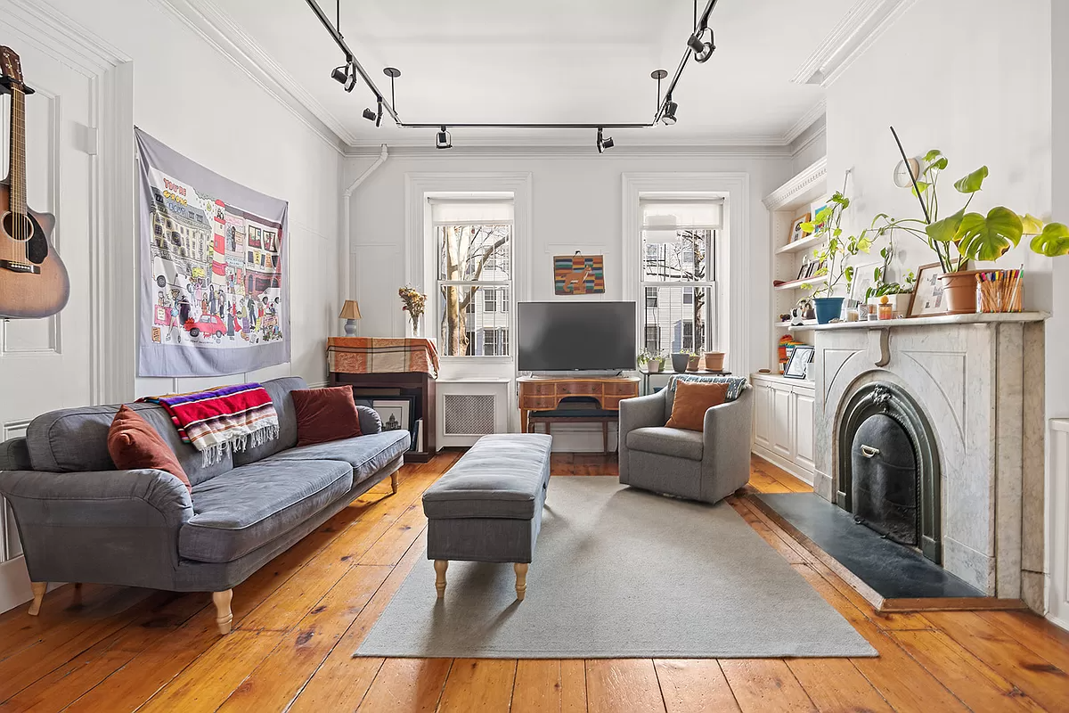 living room with wide planked floorboards and a marble mantel