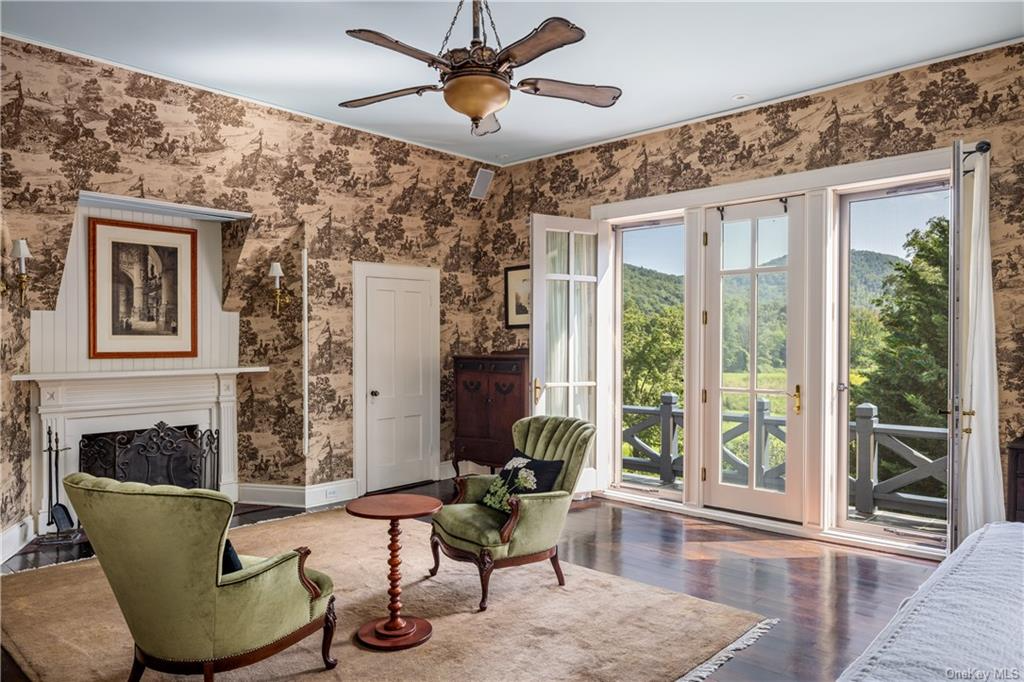 bedroom with brown toile wallpaper, a mantel, and glass doors to a balcony