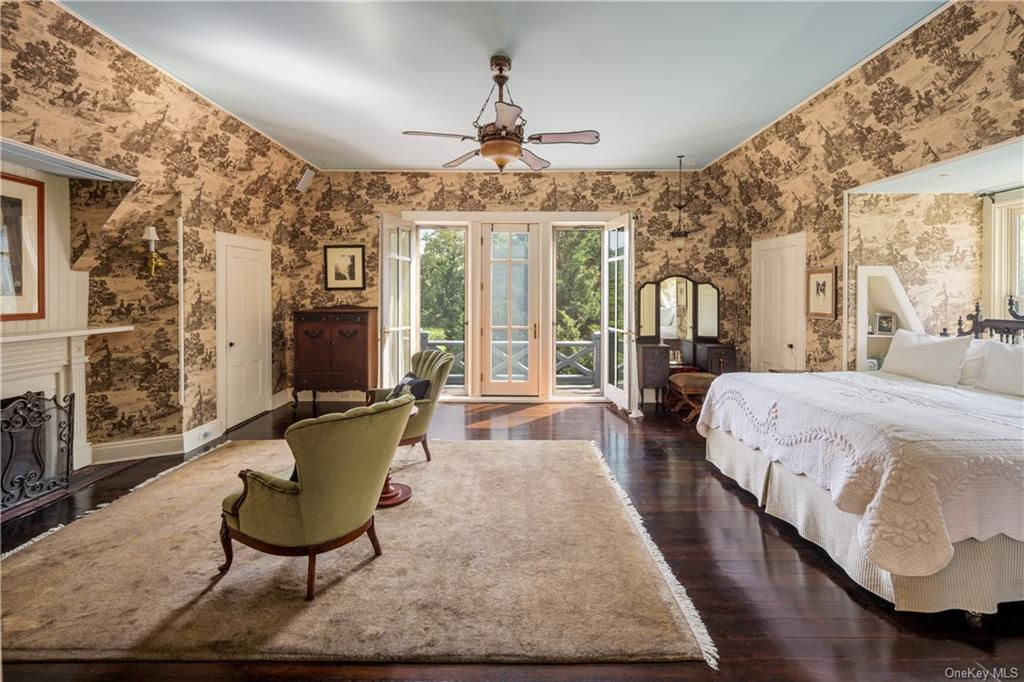 bedroom with brown toile wallpaper, a mantel, and glass doors to a balcony