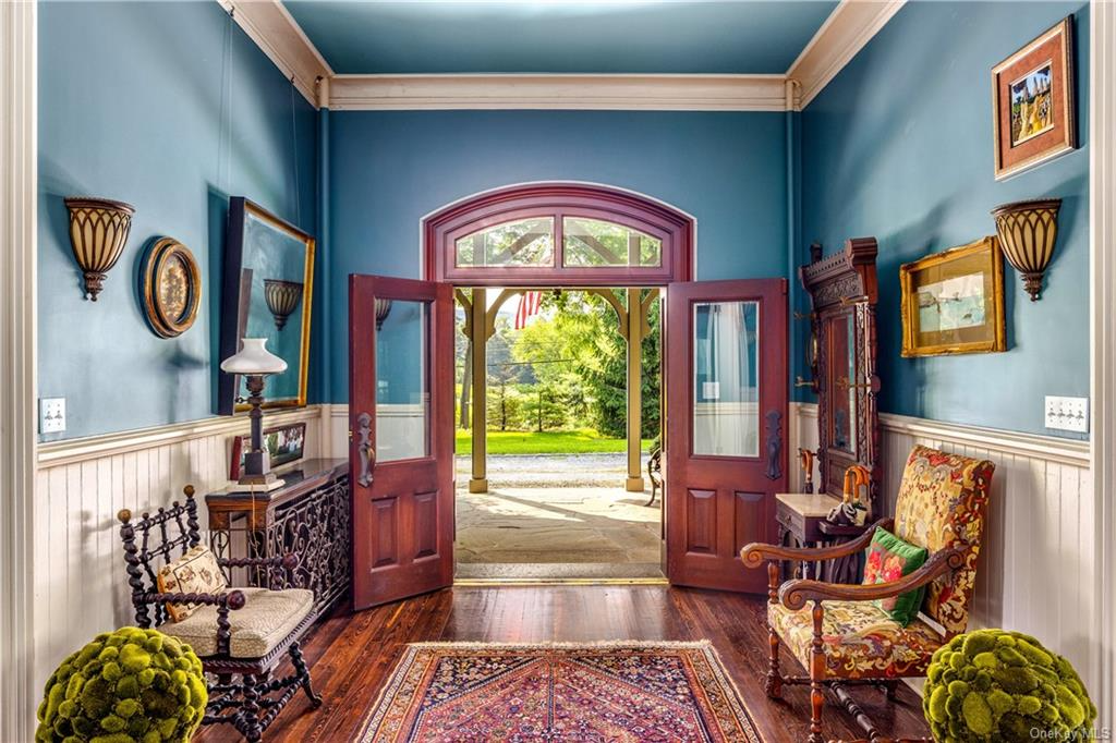 double doors open to the entry hall with wood floor and wainscoting