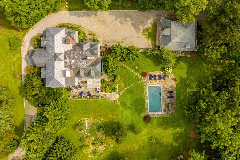 aerial view showing a garden near the house and a driveway curving past the house to the garage at the rear