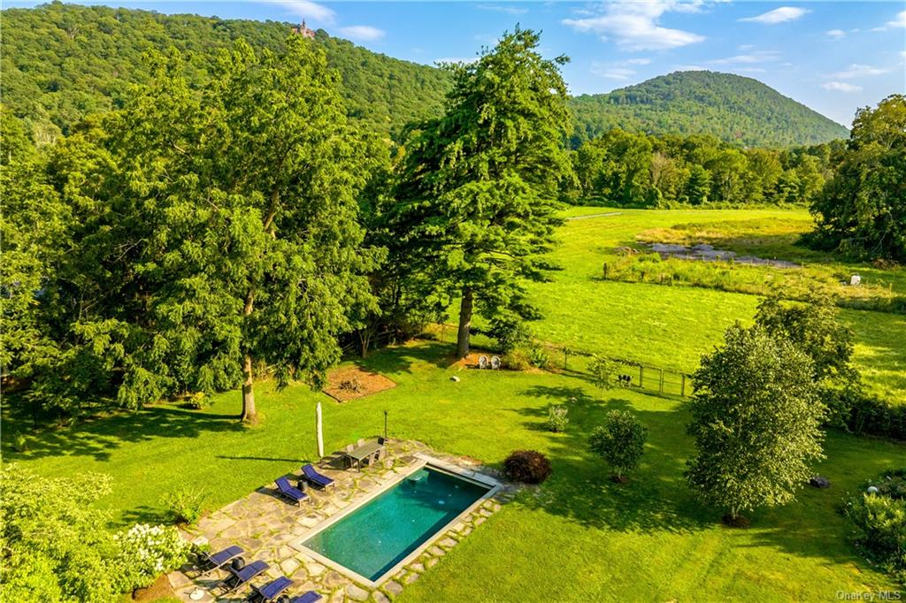 aerial view of the pool with stone surrounding and view of green fields