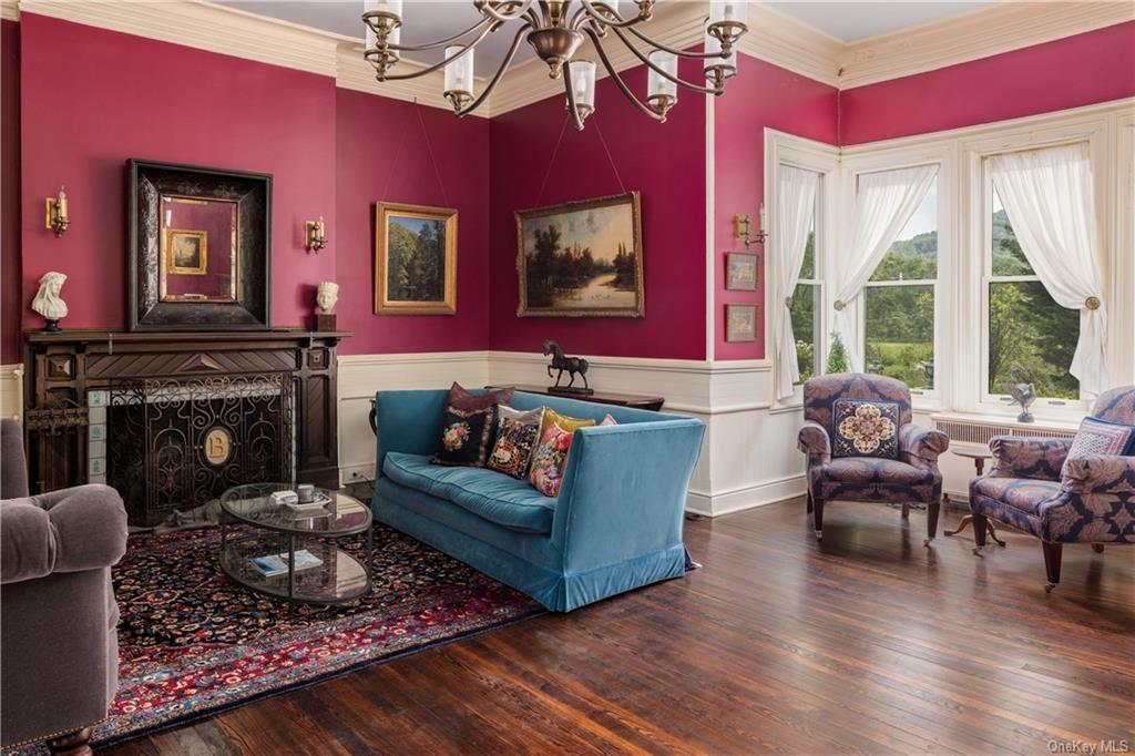 parlor with magenta walls, white wainscoting and a mantel