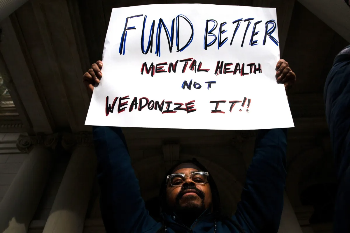 An advocate held a sign reading "Fund Better Mental Health Not Weaponize It!!" during a rally outside City Hall against Mayor Adams' plan to involuntarily hospitalize people.