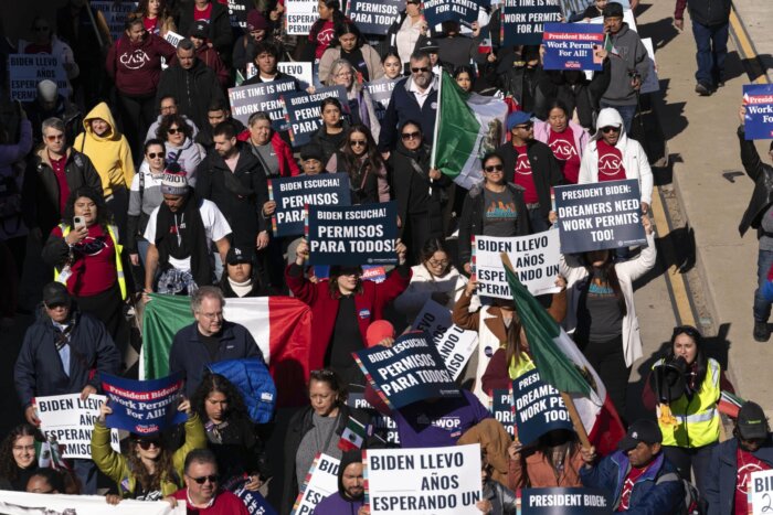 people marching with signs about work permits