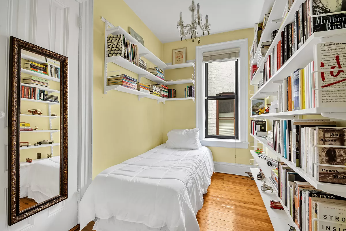 narrow bedroom with a window and wood floor