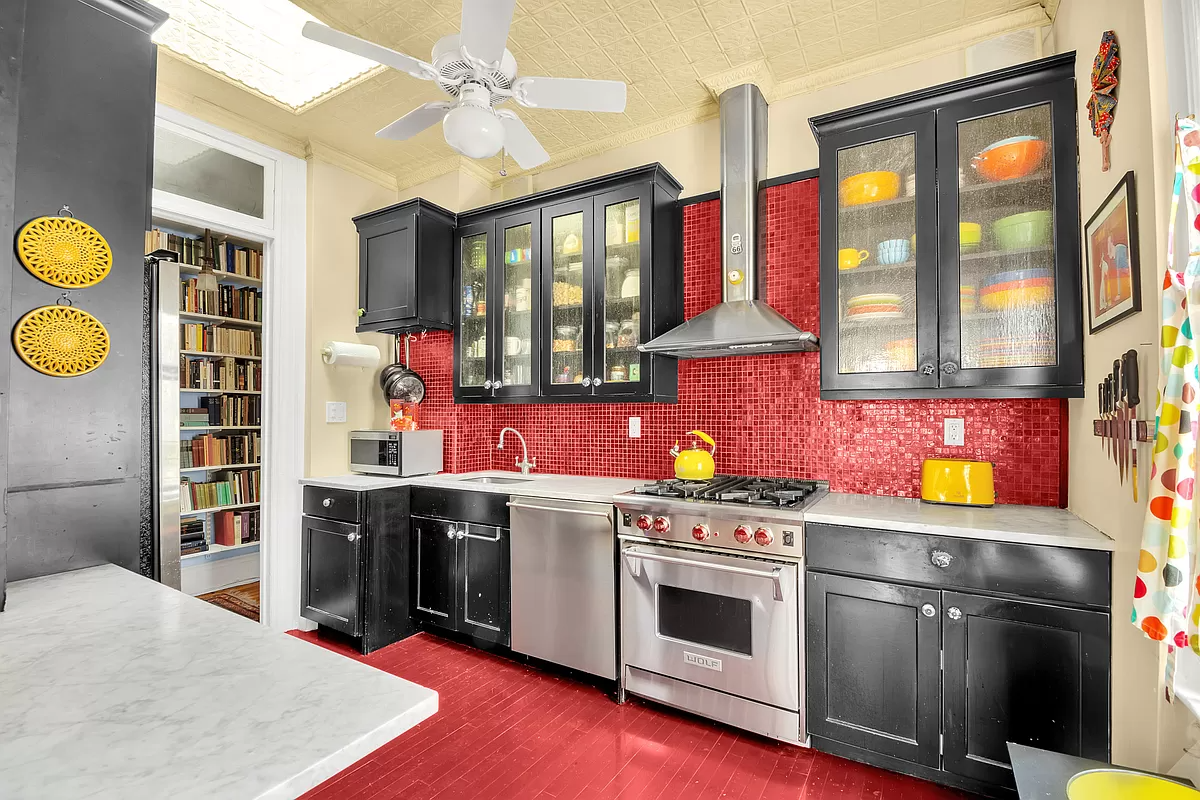 kitchen with red floor and red backsplash, tin ceiling and black cabinets