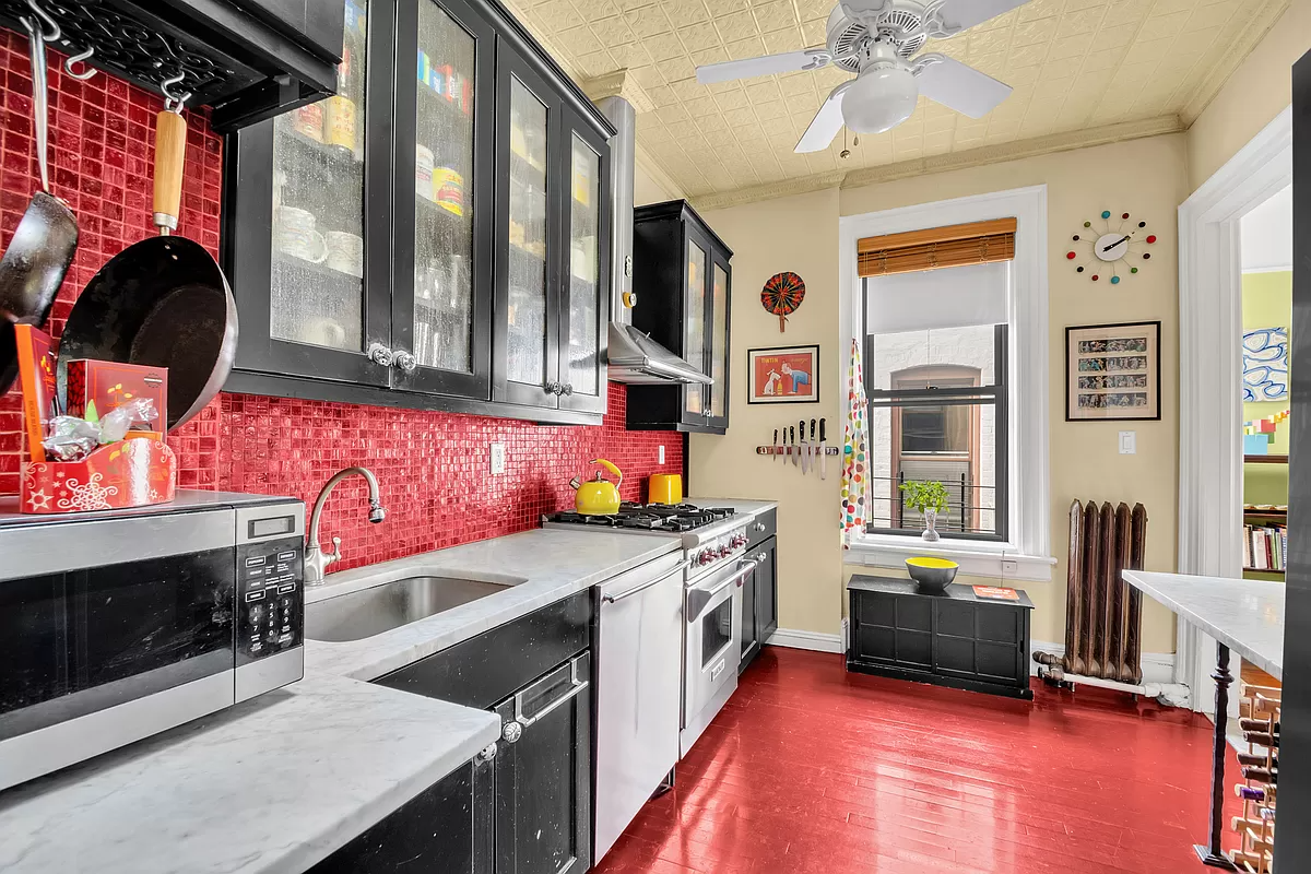 kitchen with red floor, red backsplash and black cabinets