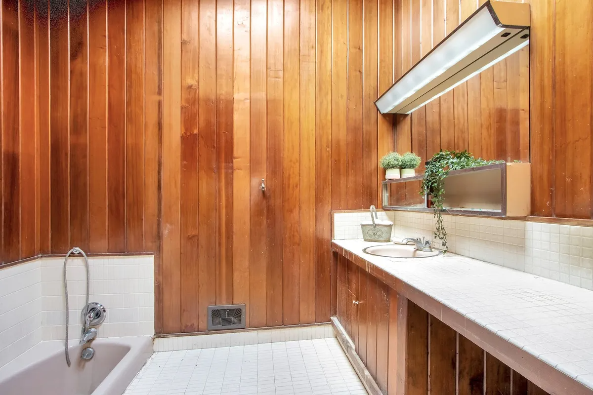 bathroom with sunken tub and wood walls