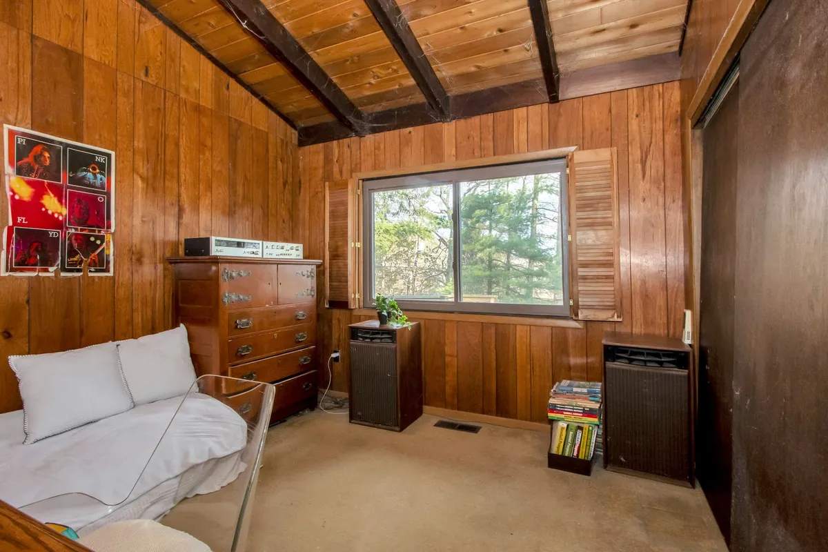 bedroom set up as den with wood walls and ceiling and sliding doors on a closet