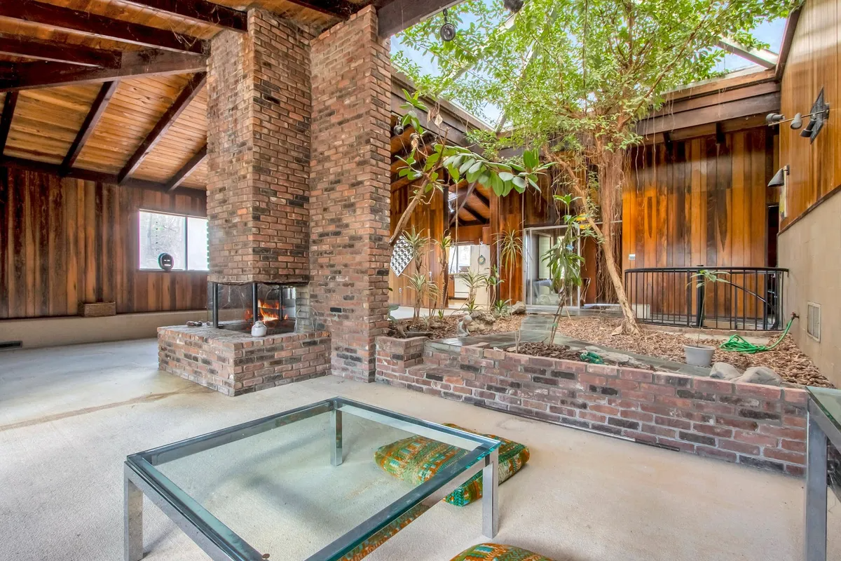 open plan living space with view of interior tree and brick fireplace