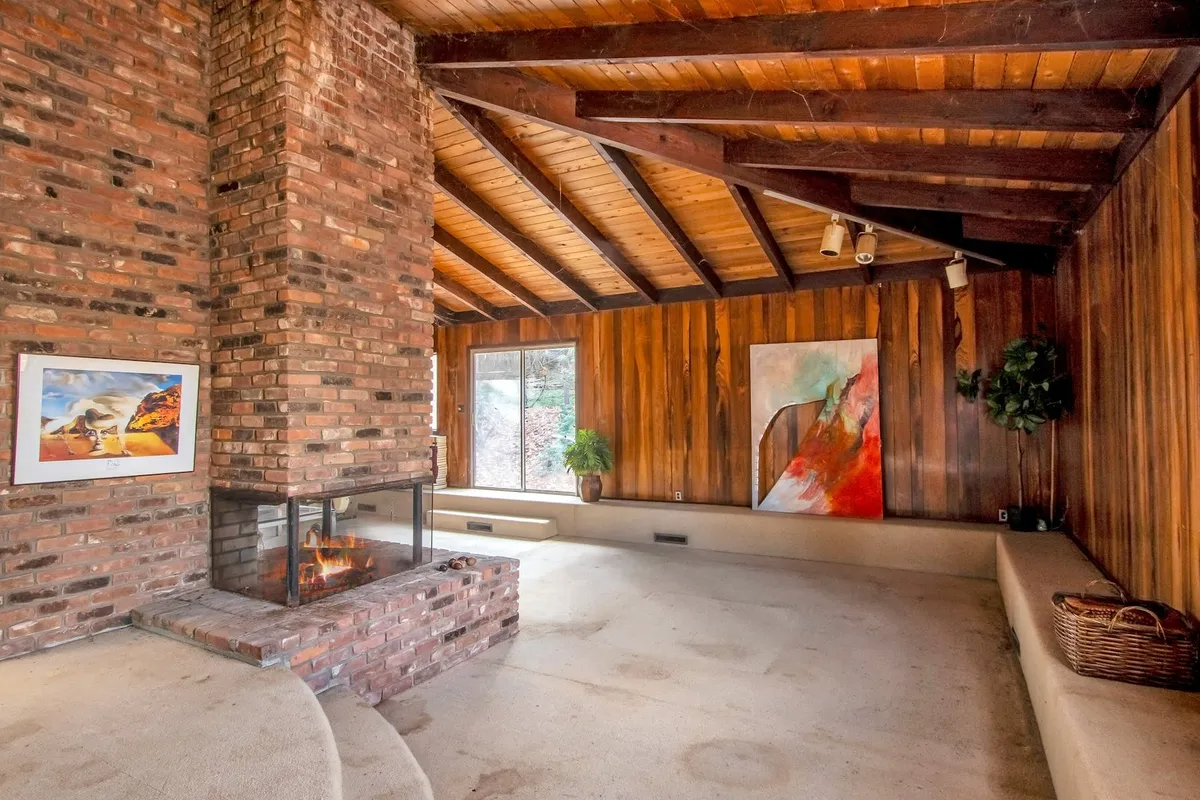 sunken living room with wood walls and ceiling and a brick fireplace