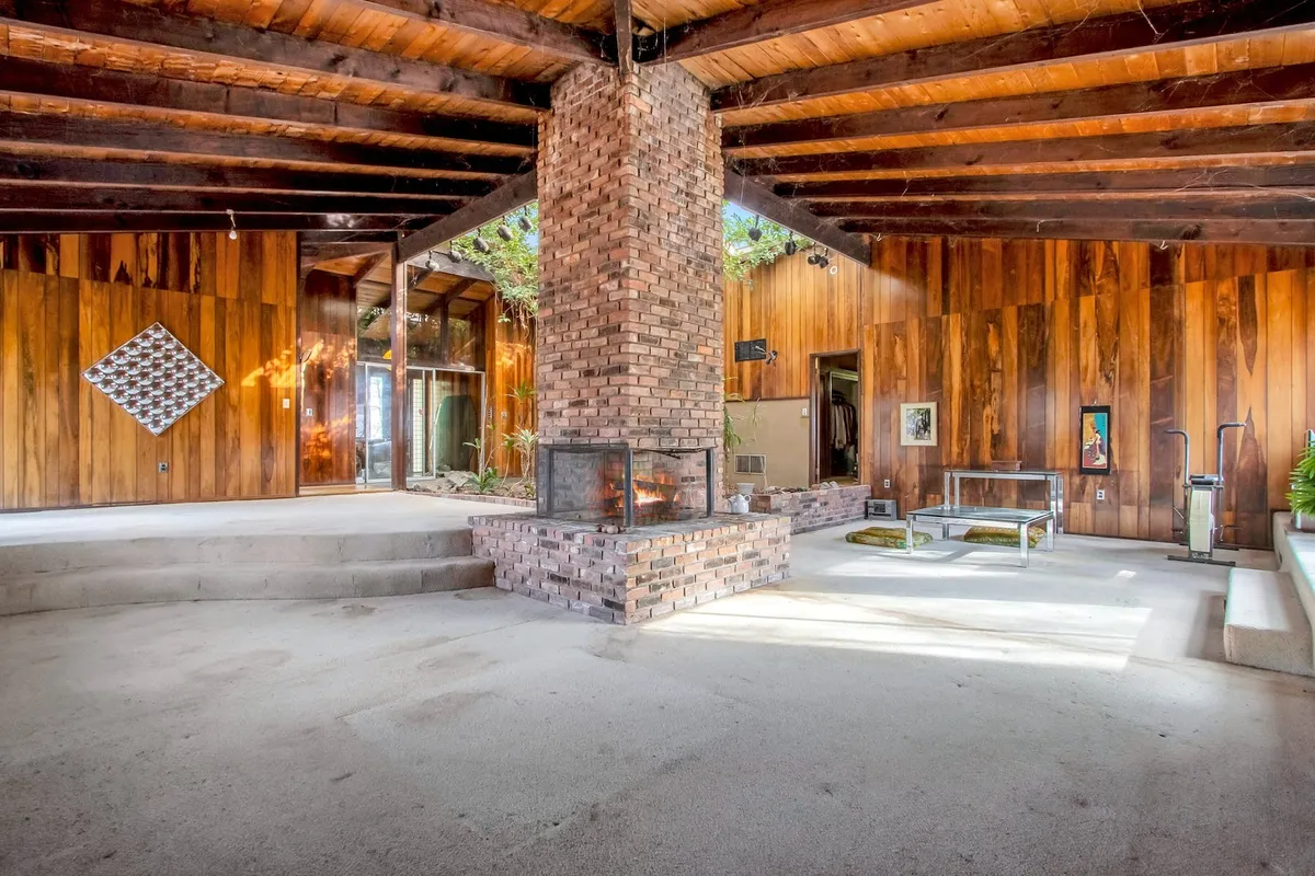 open plan living area with central fireplace and wood walls and ceiling