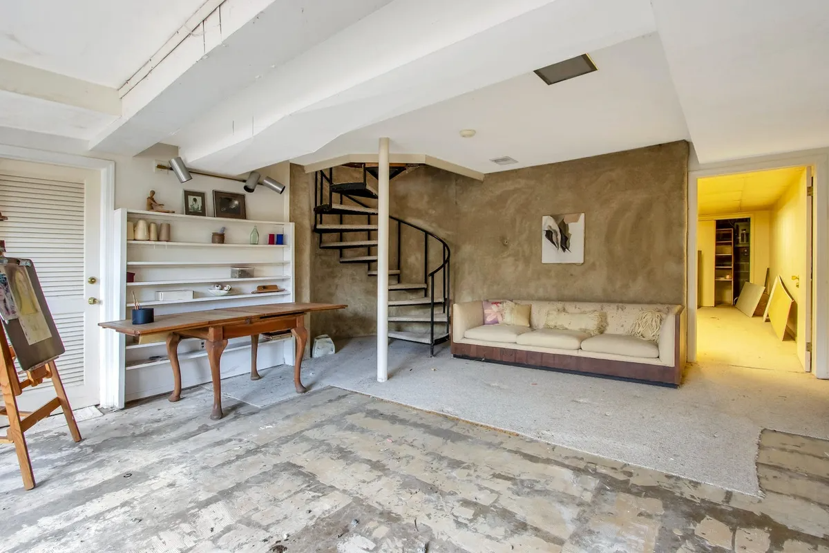 basement den with curved staircase and cement floor