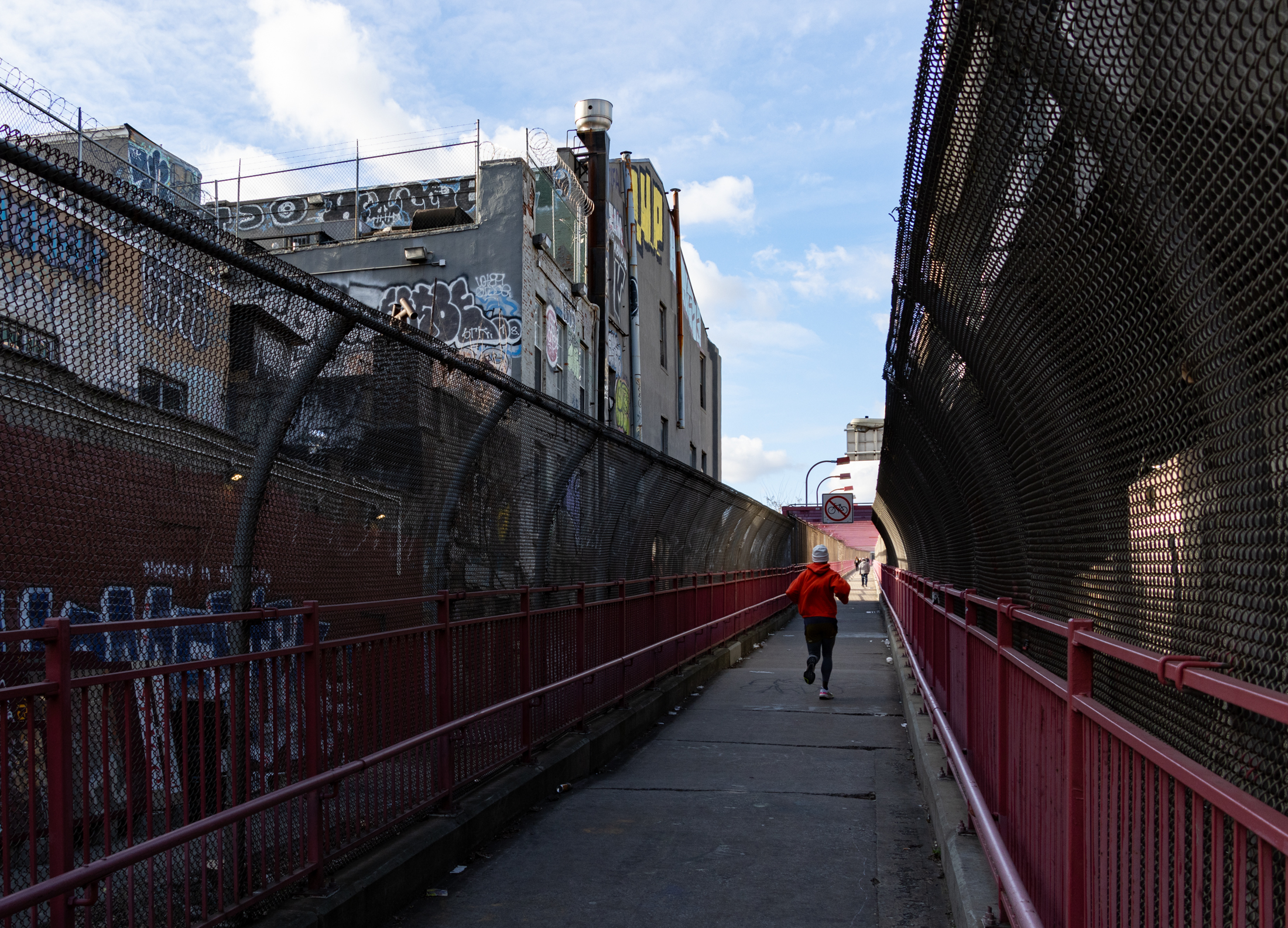 a runner passes by the rear of the building on the williamsburg bridge pedestrian walkway