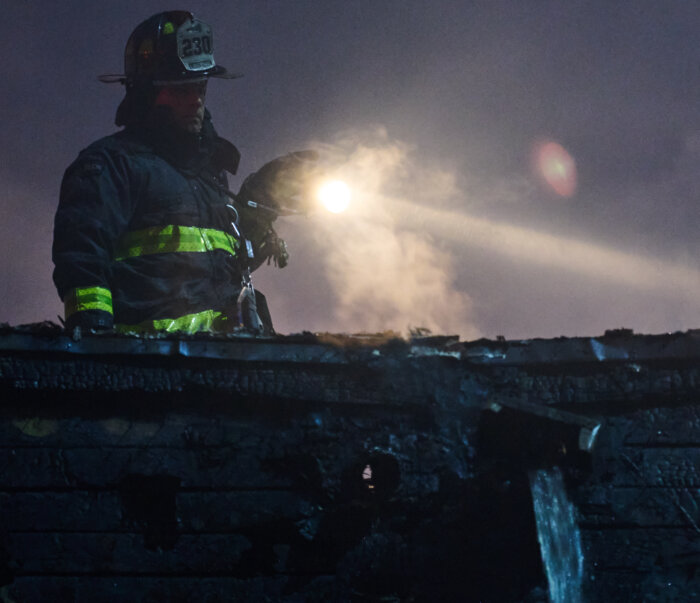 A firefighter shines a light into the building