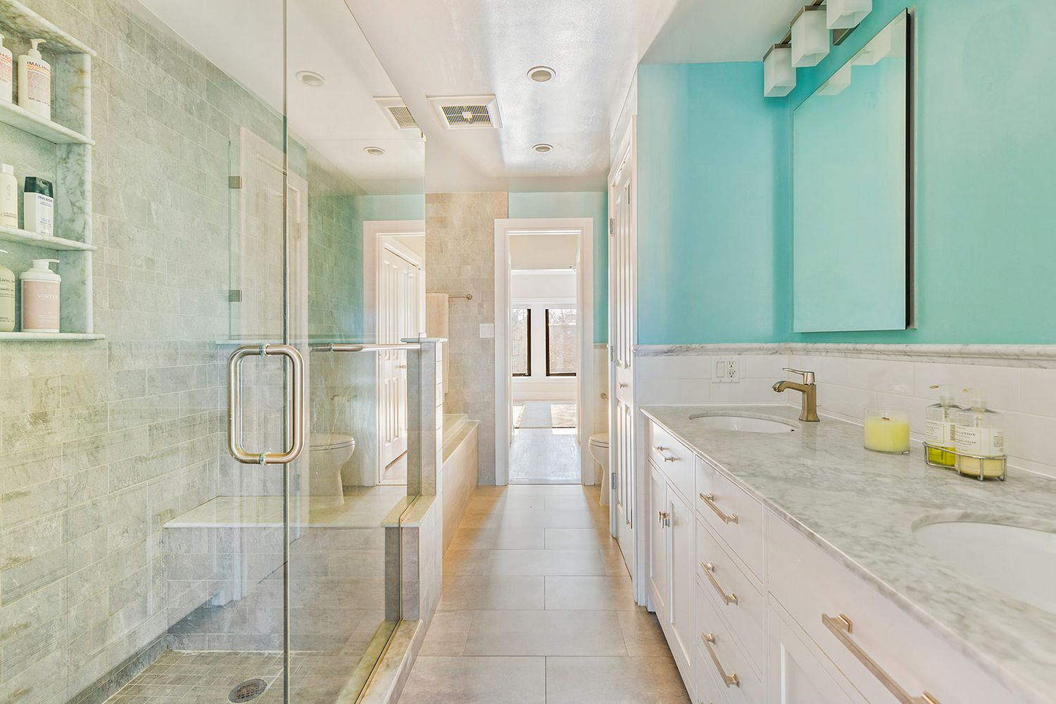 bathroom with double vanity, glass shower and a tub