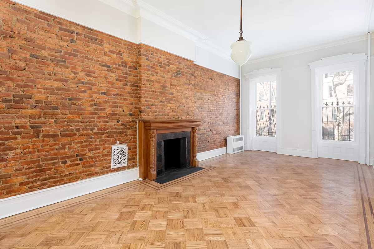 parlor with exposed brick wall and a wood mantel