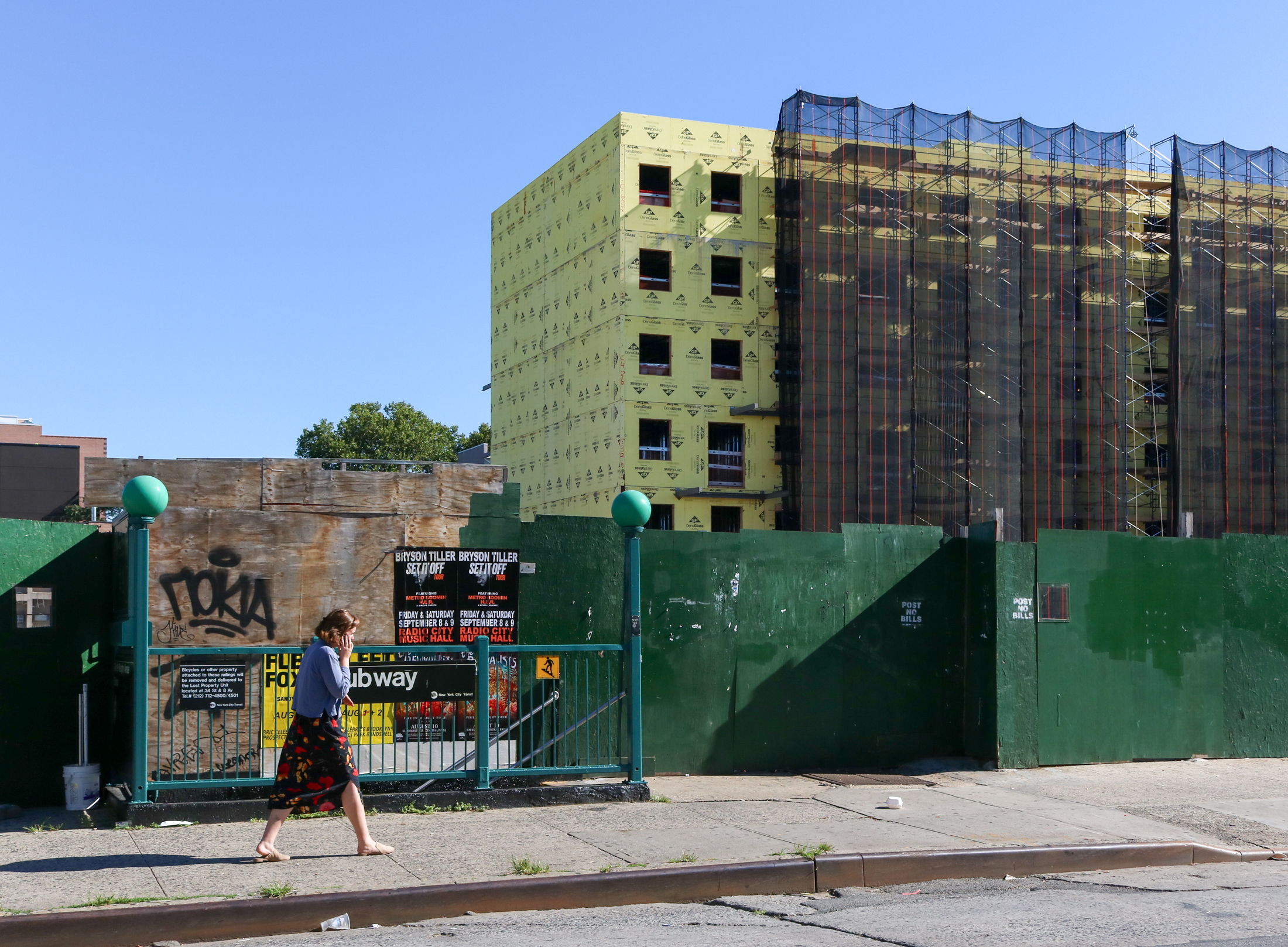 woman walks by a subway stop with construction in the background