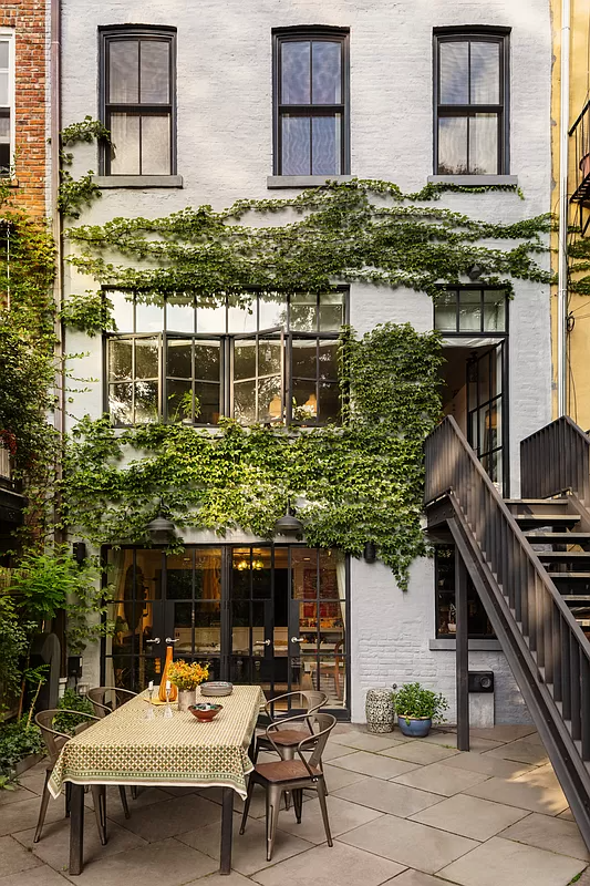 view of rear facade in summer with vines growing across the white painted brick