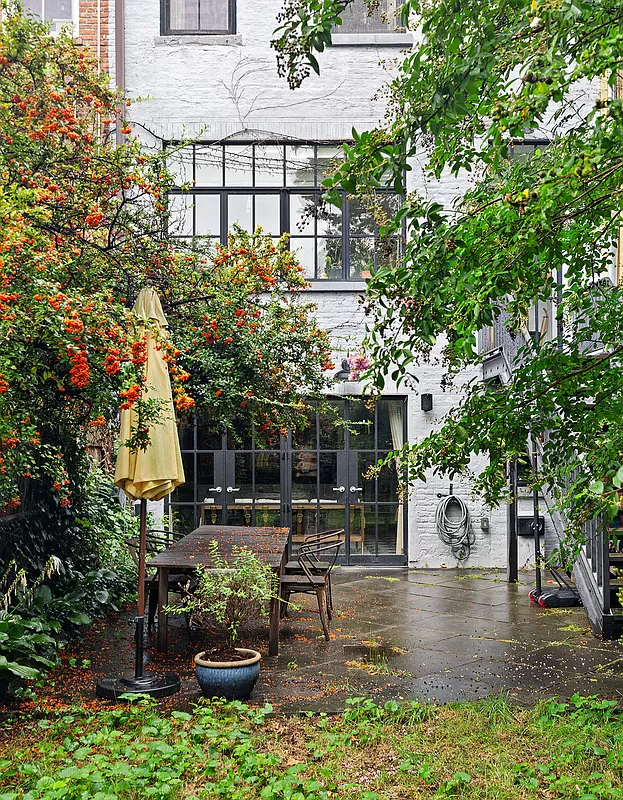 view of rear facade with brick painted white and wall of glass on garden level