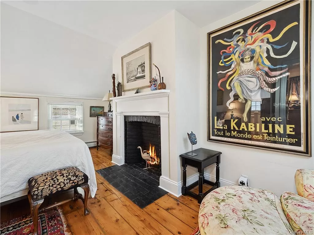 bedroom with white mantel and wide planked wood floors