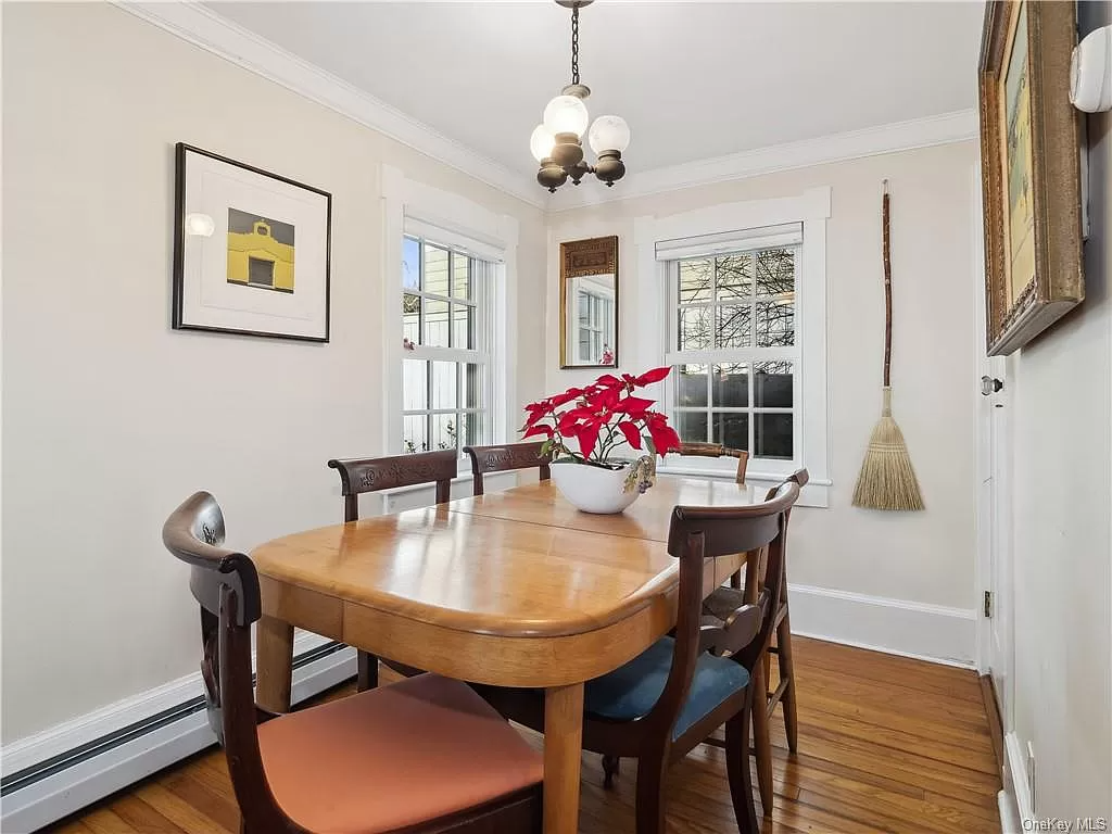 dining room with wood floor, two windows and baseboard heating