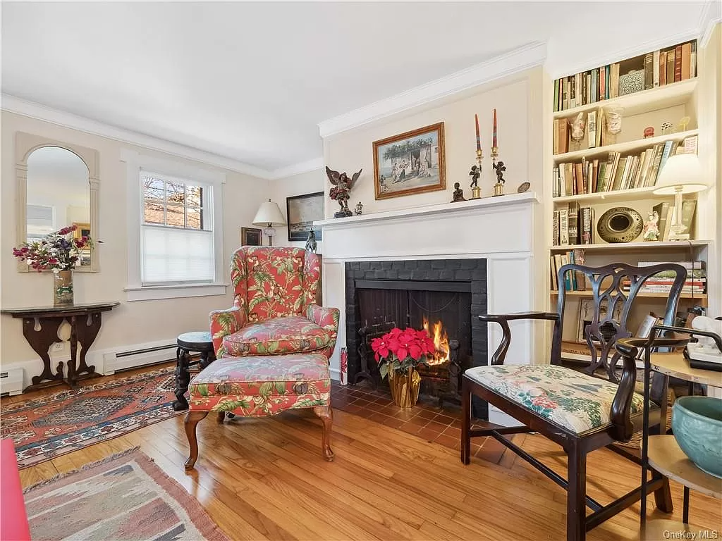 parlor with white mantel, wood floor, and baseboard heating