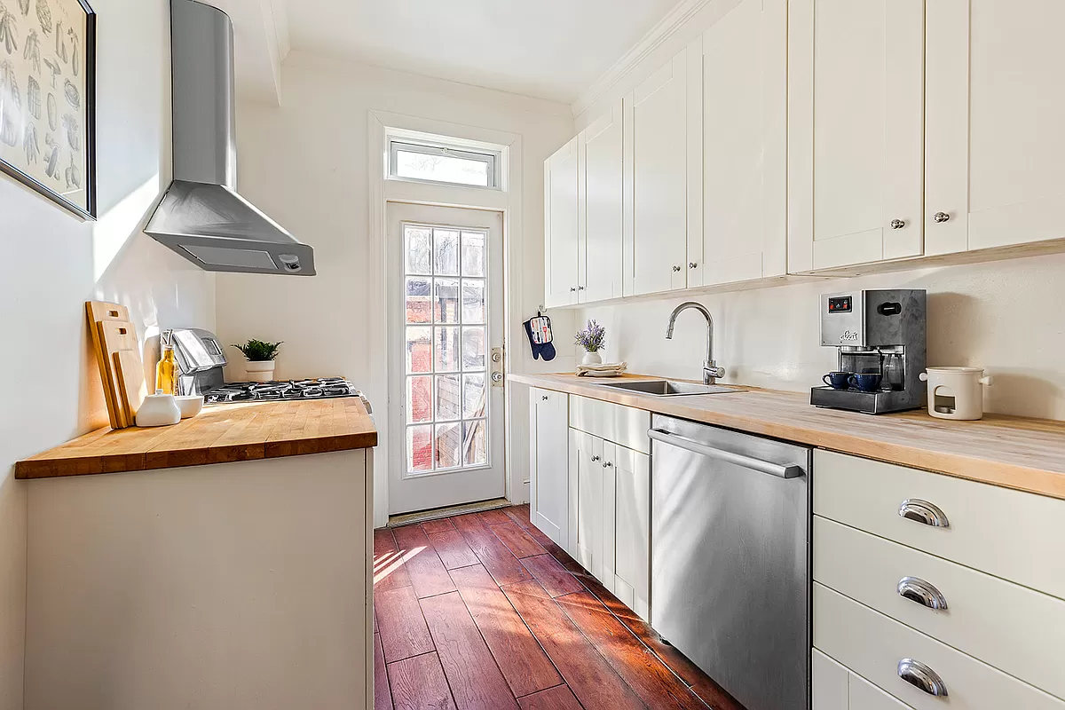 parlor level kitchen with white cabinets and a butcher block counter