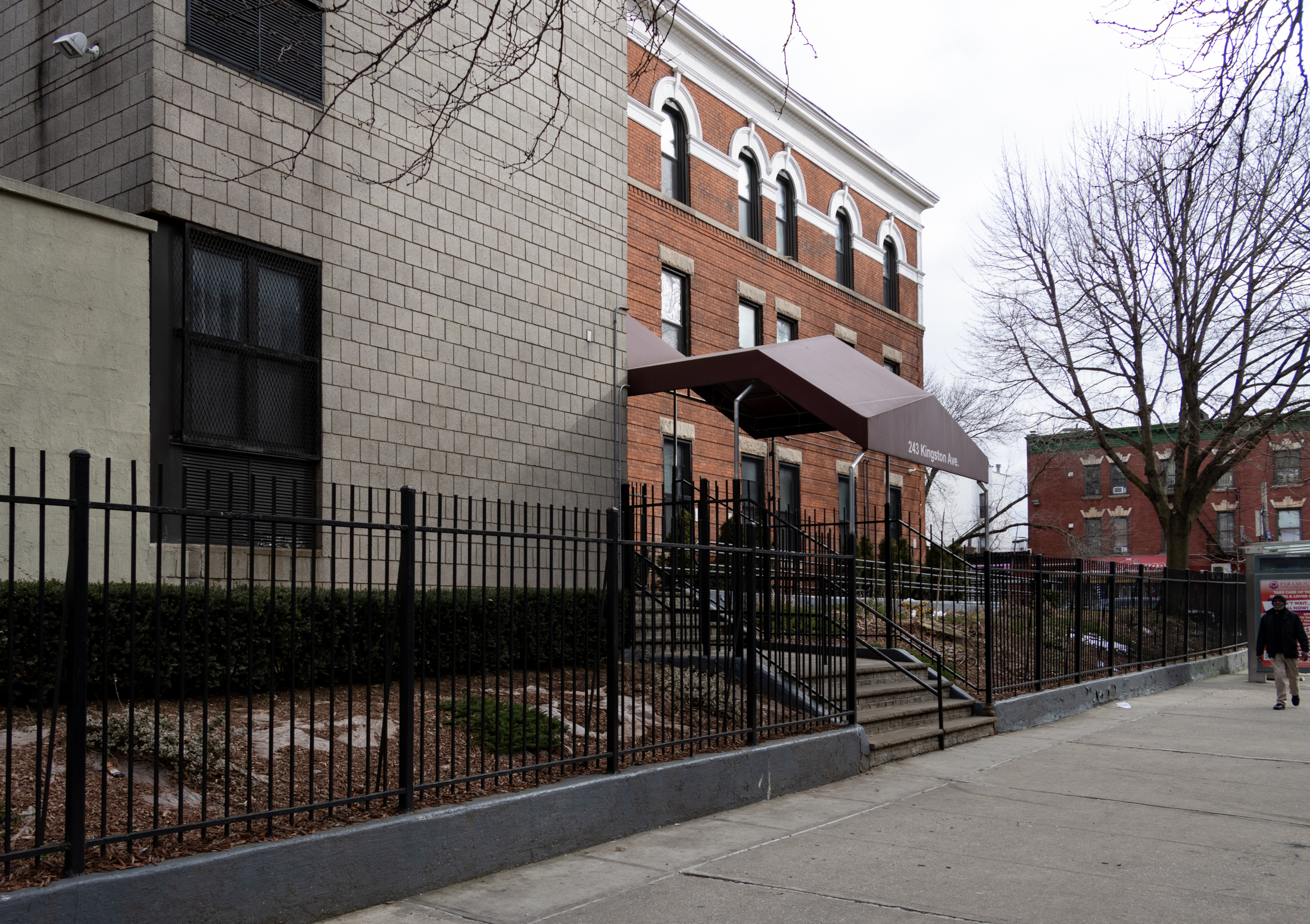 view along kingston avenue showing a modern awning and the original brick building