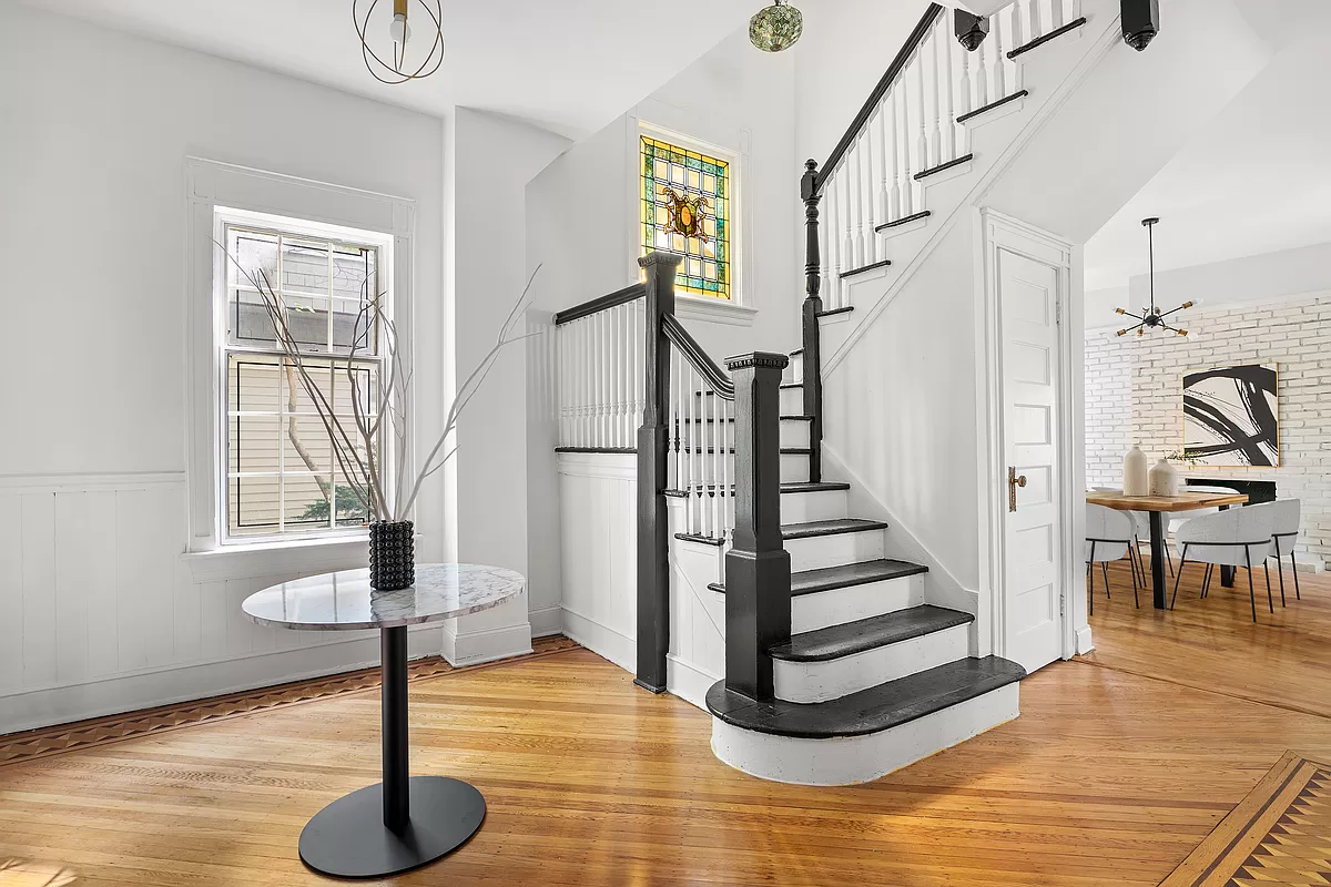 entry with wood floor and stair with stain glass window on landing