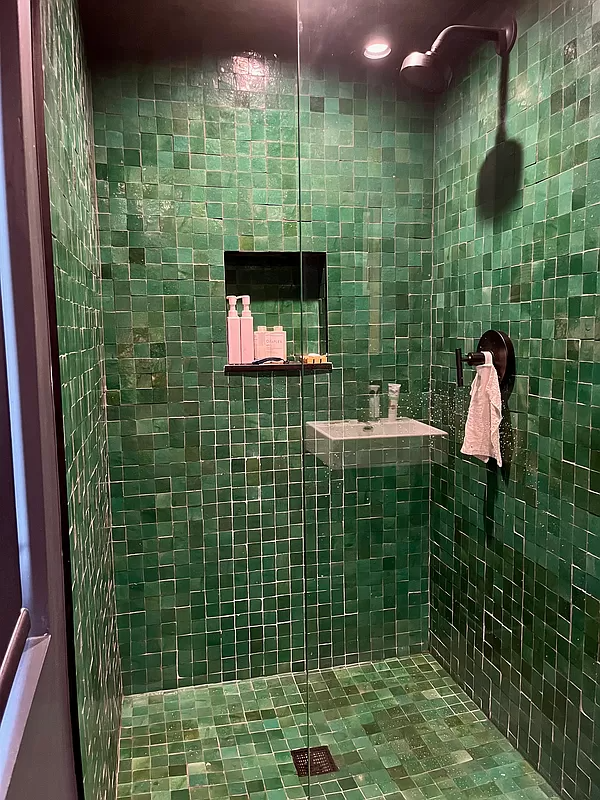 shower with glass door and green tile