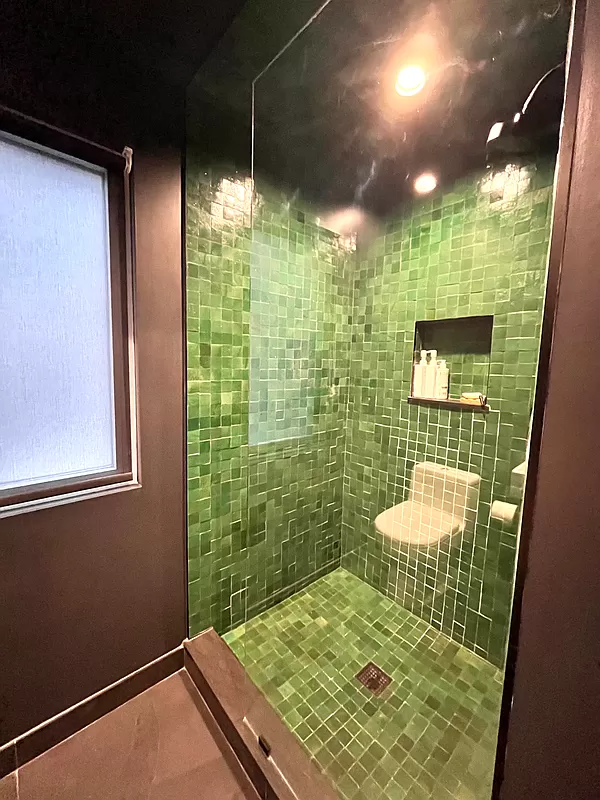 bathroom with walk-in shower with green tile